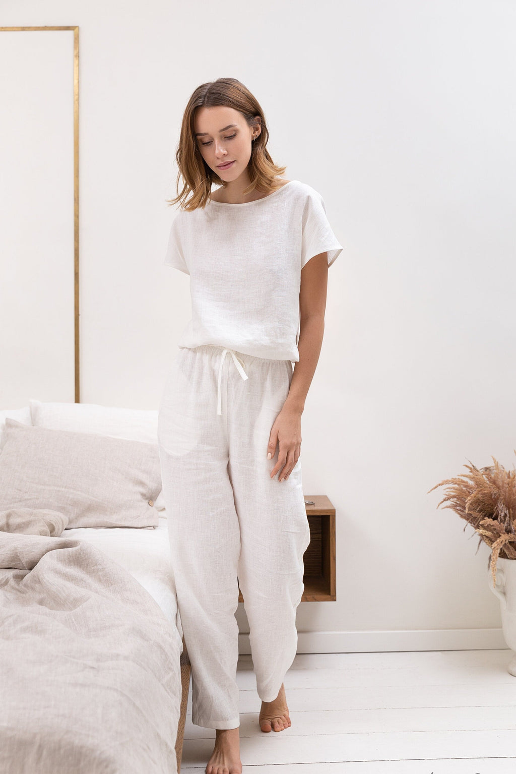 Woman wearing a white outfit in a minimalistic room.