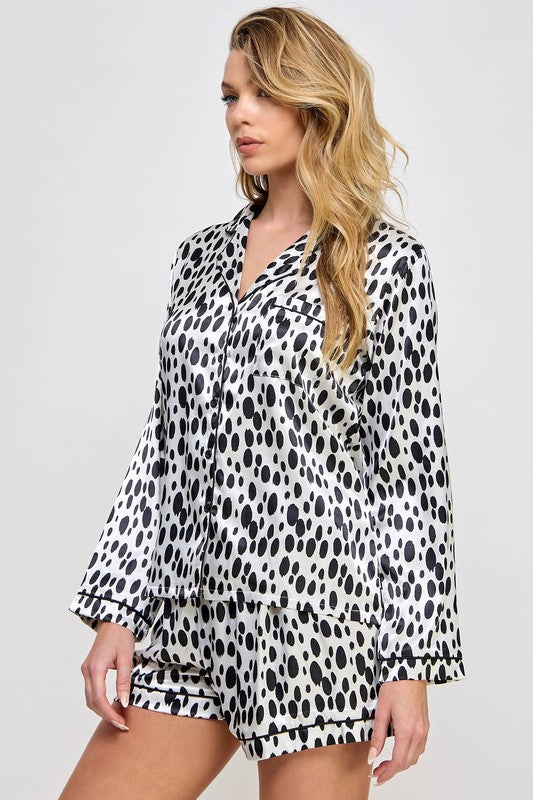 Woman wearing a black and white polka dot pajama set on a plain background