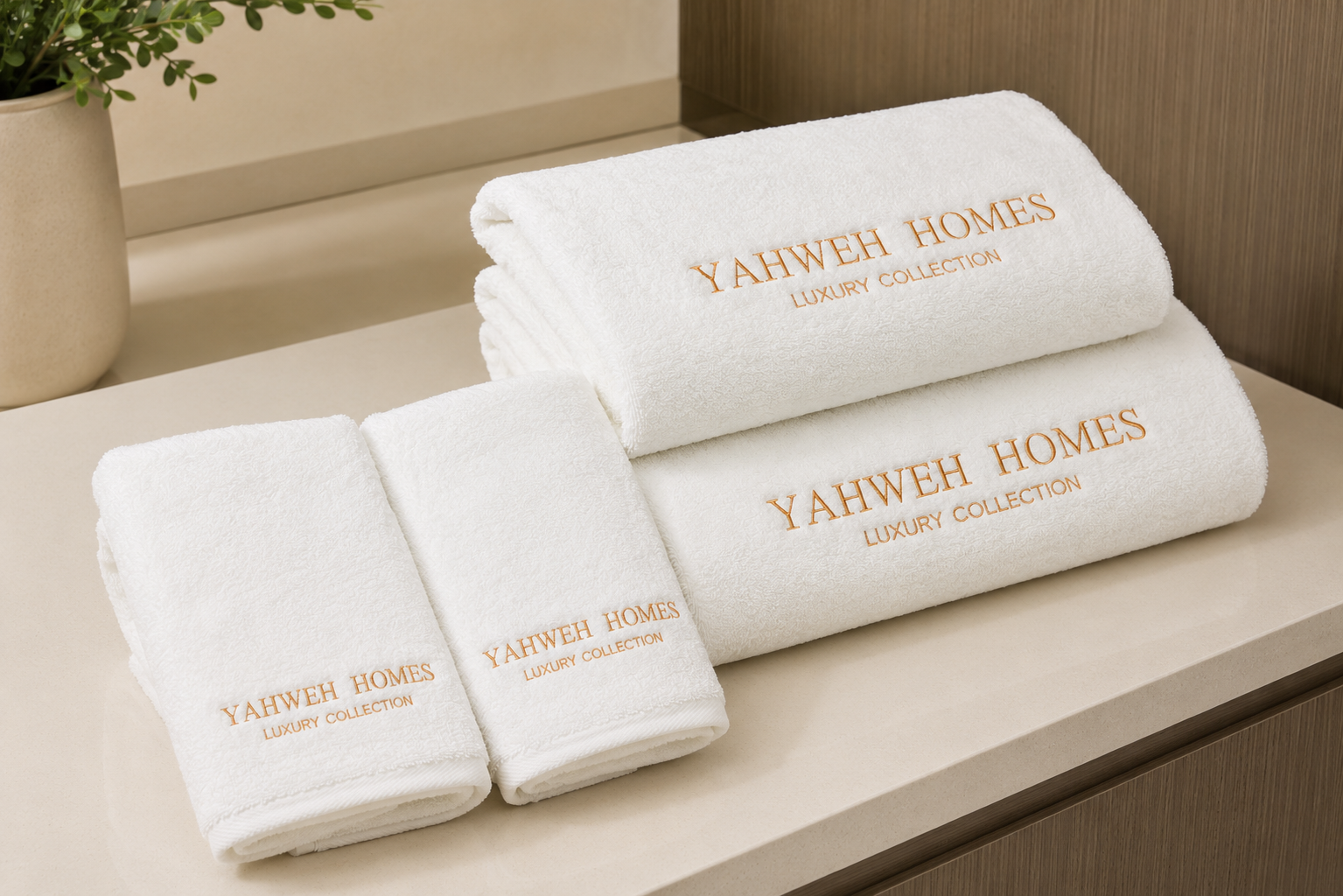4 piece White towel set with 'Yahweh Homes Luxury Collection' text on a wooden surface
