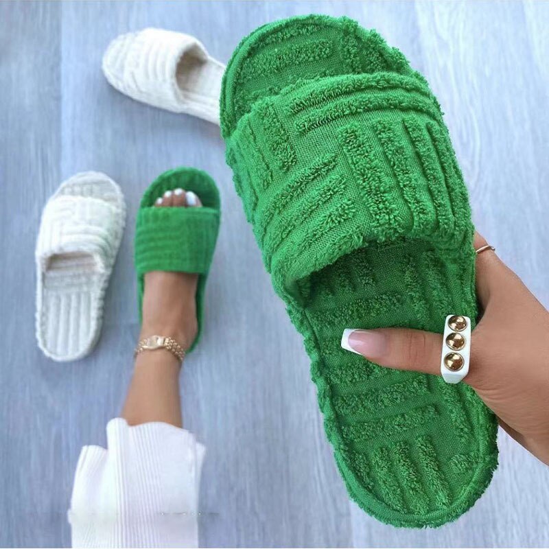Green textured slippers hed on a grey background