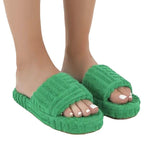 Green slippers worn by a person on a white background