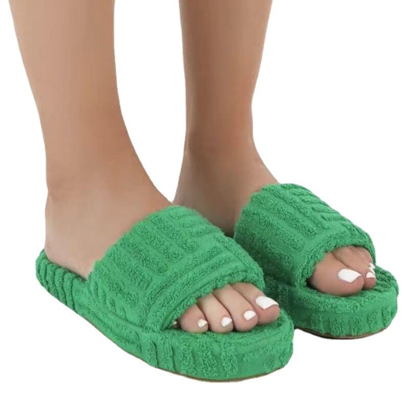 Green slippers worn by a person on a white background