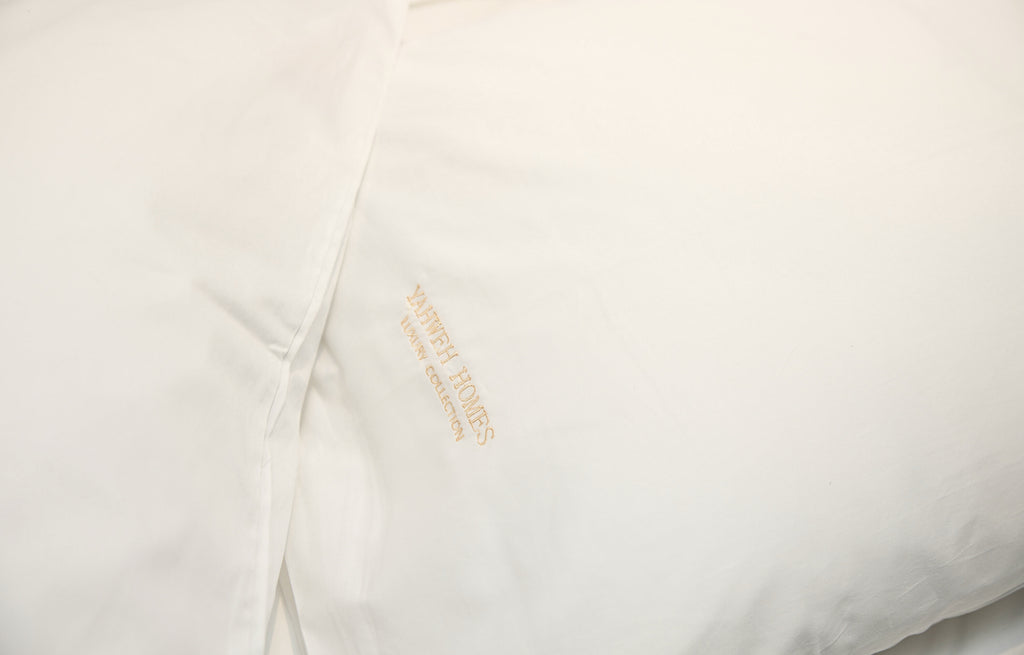 Close-up of a white pillow case with Yahweh Homes Embroidery.