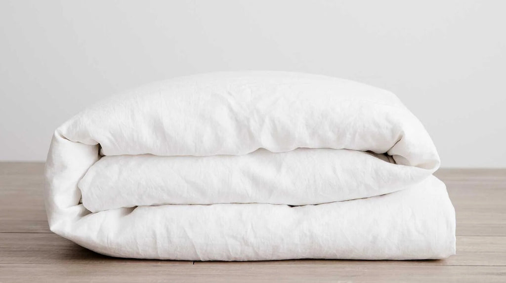 Folded white Duver Cover on a wooden surface with a light gray background