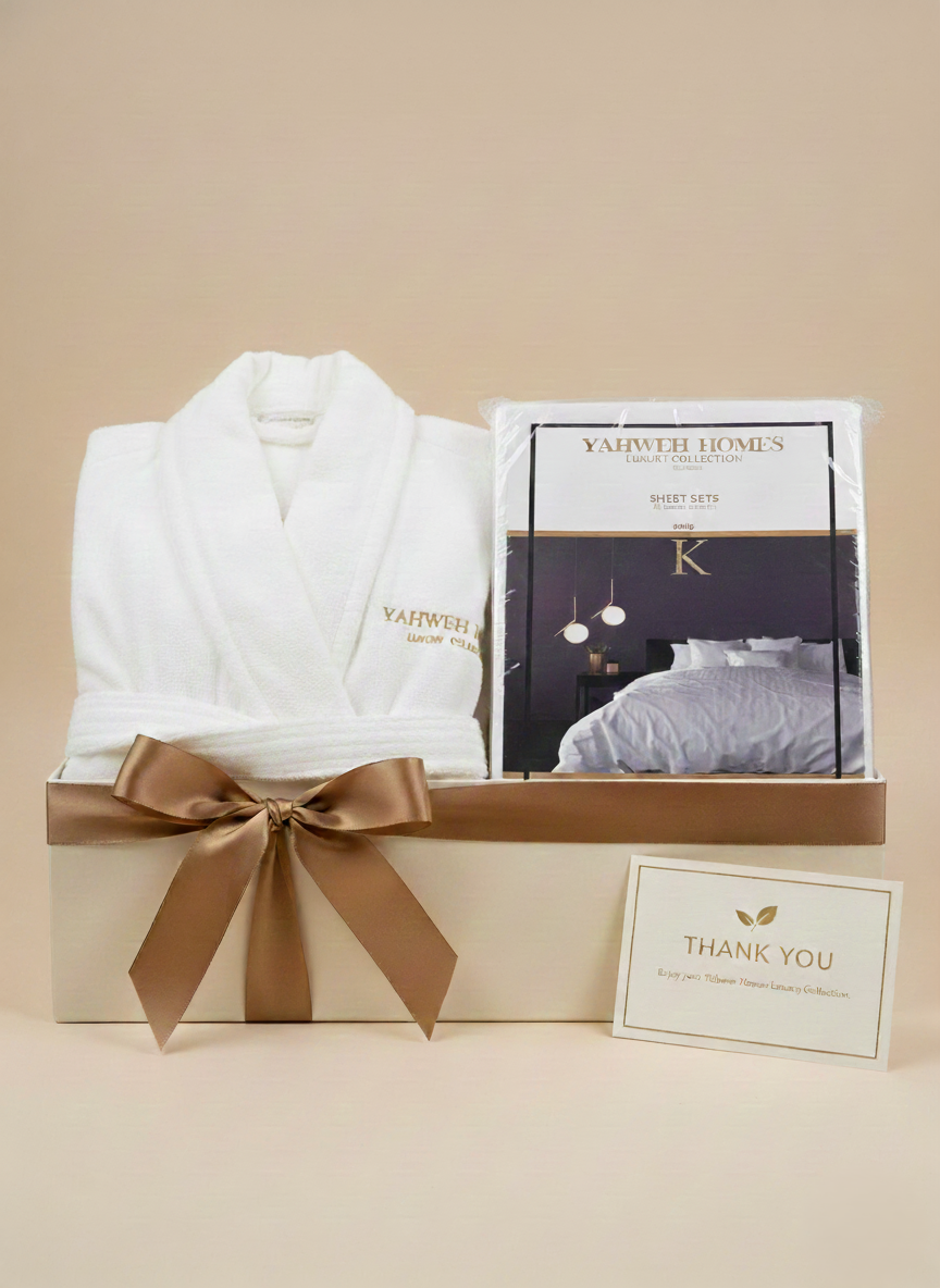 Gift box with white robe, bedsheets, and 'Thank You' card on a beige background