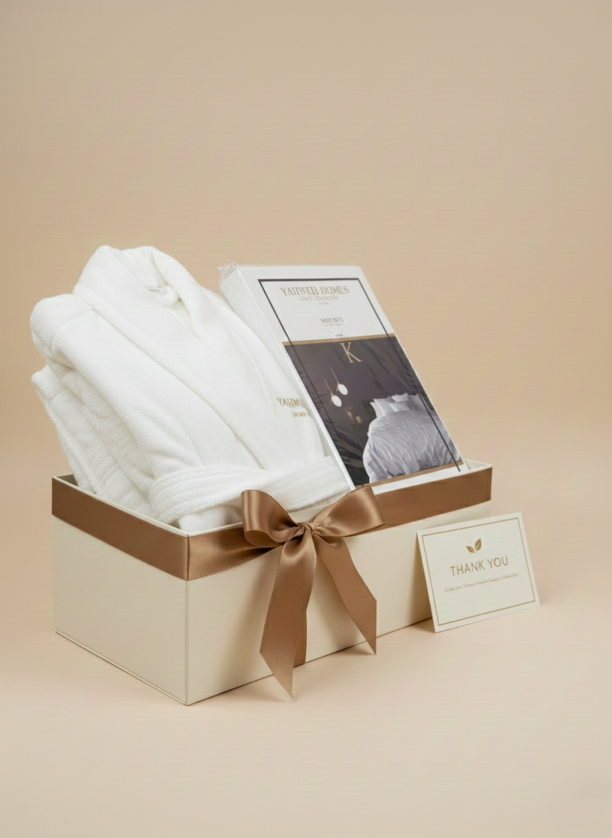 Gift box with white bath robe, a white Queen Size bedsheet, and a card on a beige background