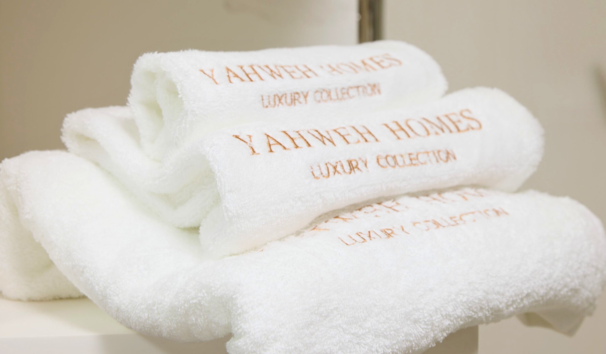Stack of white towels with 'YAHWEH HOMES' branding.