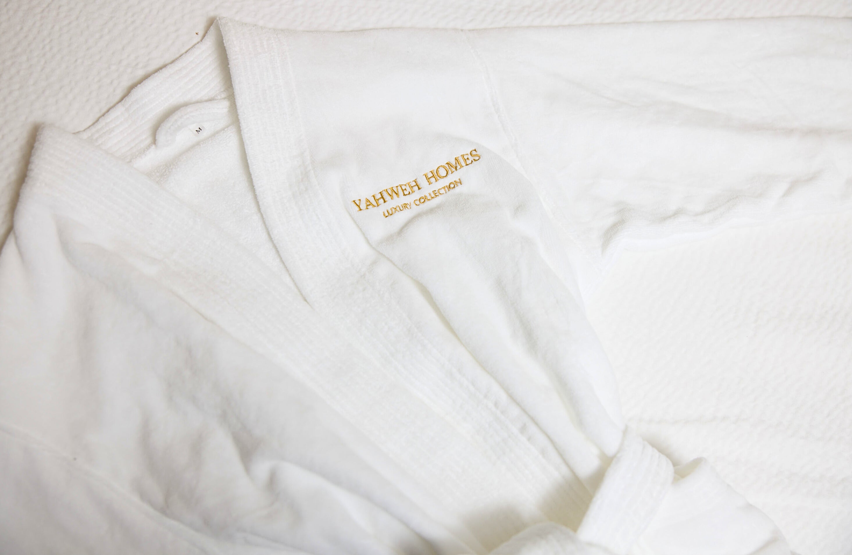 White robe with 'Yahweh Homes' branding on a light background