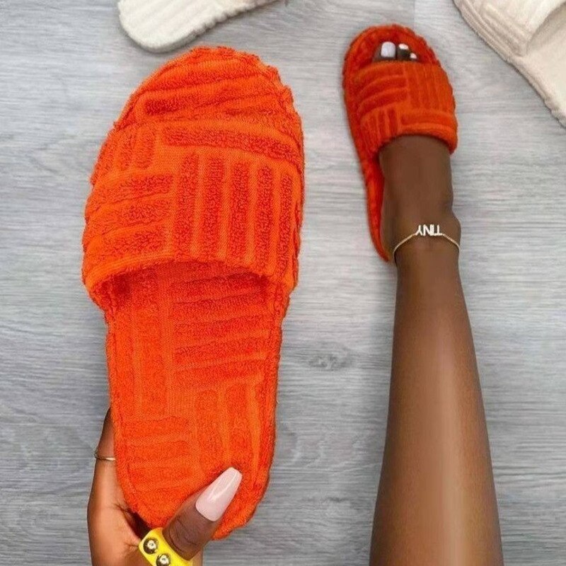Orange textured slippers held on a gray surface
