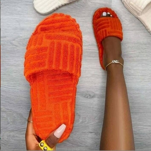 Orange textured slippers worn on a gray wooden floor.