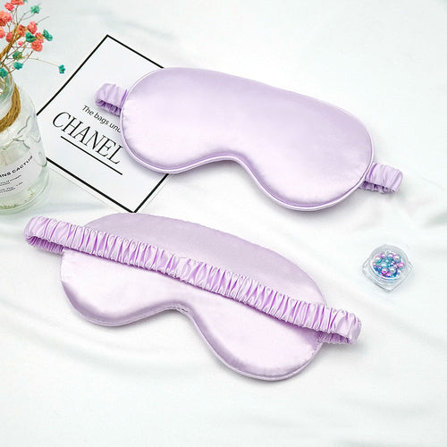 Two purple silk eye masks on a white surface 