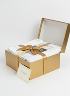 Gift set with towels, bedsheet, and a card in a gold box on a white background