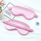 Two pink satin eye masks on a white surface .