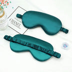 Two teal silk eye masks on a white surface .