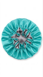 Turquoise satin hair bonnet with a silver interior on a white background 