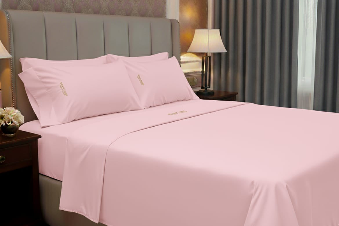 Pink bed sheets and pillows on a bed in a bedroom setting.