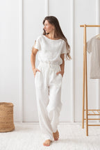 Woman wearing a white outfit standing in a minimalistic room.