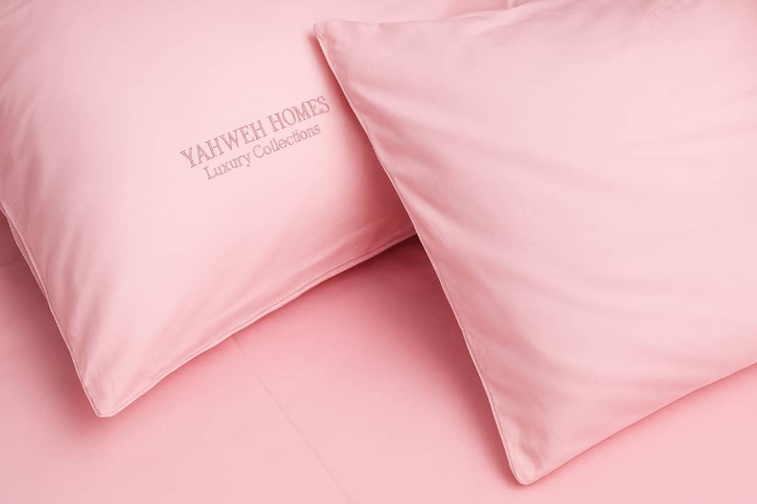 Pink pillows with 'YAHWEH HOMES' branding on a pink background